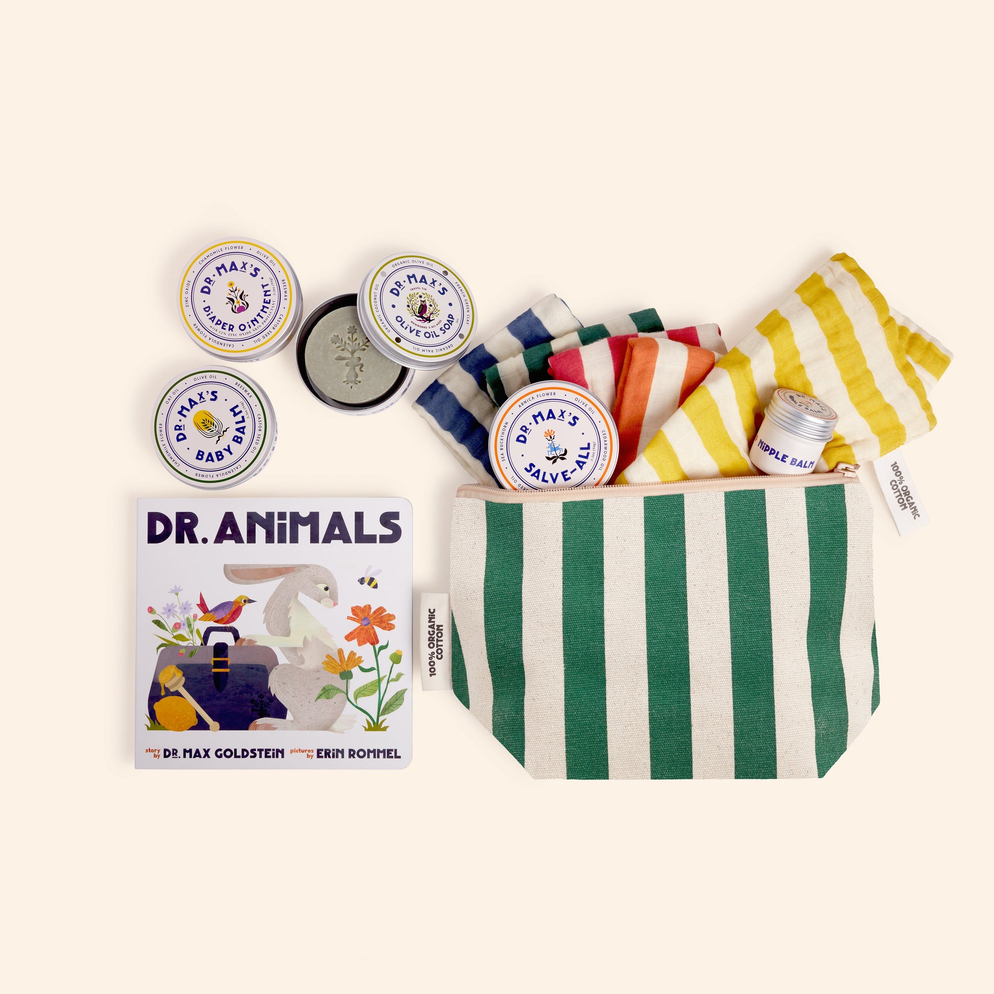 The Dr Maxs New Parent Gift Box includes daily essentials: a green-and-white striped pouch, matching towels, skincare tins, a Baby Balm Diaper Ointment stick, and the Dr. Animals children’s book, all displayed on a light background.