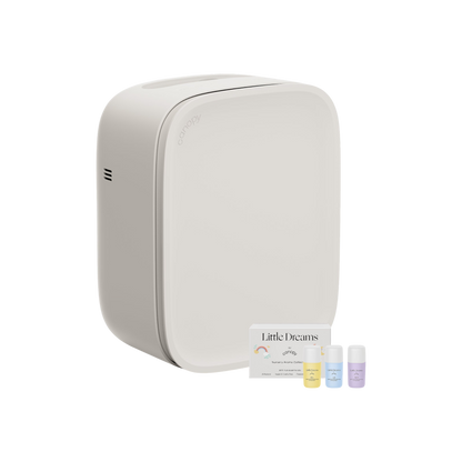 A sleek, white rectangular diffuser with rounded edges sits beside three small essential oil bottles and a "Little Dreams" card, creating a serene nursery vibe. Pair with the Canopy Nursery Air Purifier for ultra-clean air using HEPA-13 filtration.