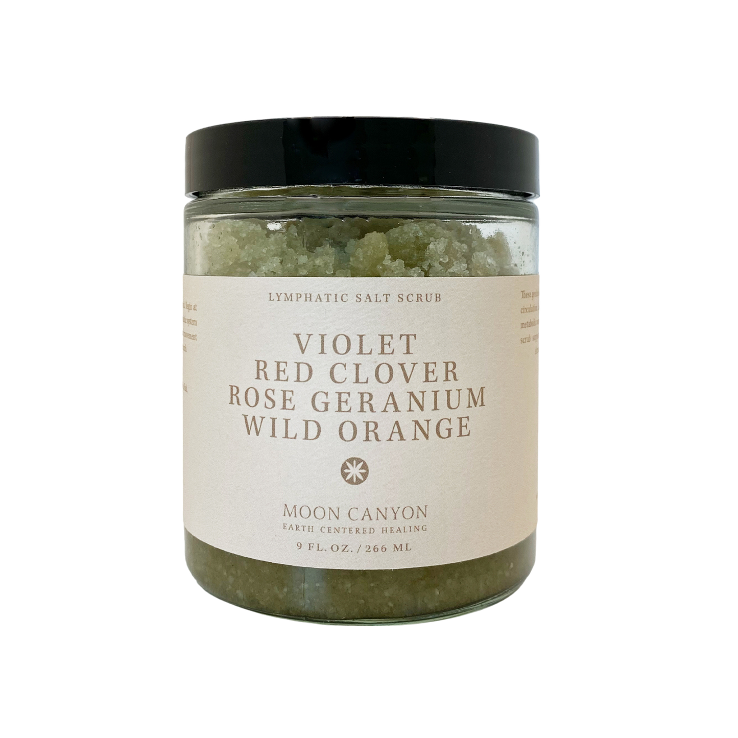 A glass jar with a black lid contains the Violet, Red Clover, Rose Geranium & Wild Orange Lymphatic Salt Scrub designed for skin health. The label reads "Moon Canyon Healing," featuring ingredients such as violet, red clover, rose geranium, and wild orange. It holds 9 fl. oz./266 ml of product, promoting effective detoxification and lymphatic drainage.
