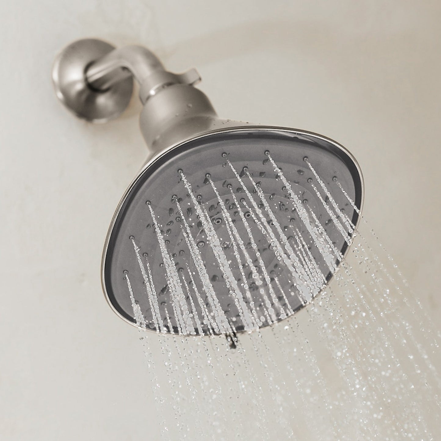 A close-up of the Canopy Filtered Showerhead, finished in modern silver and mounted on a light bathroom wall, spraying multiple streams of water. Fulfilled by Canopy for convenience and peace of mind.