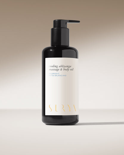 A sleek black bottle with a pump dispenser, labeled "Cooling Body Oil" and "Ayurvedic Pitta Balancing," stands upright against a neutral background. Designed for lymphatic self-massage, the brand name "Surya" shines in gold at the bottom.