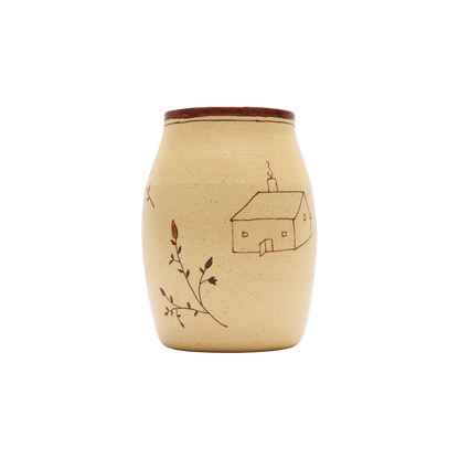 The Baile Homestead Vase by Baile is a handmade ceramic piece with a brown rim, beige surface, a simple house drawing, and hand-painted floral sprigs, shown against a plain white background.