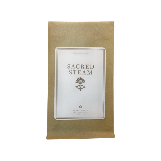 A brown paper pouch labeled "Sacred Steam Herbal Yoni Blend," has a white, rectangular label on the front featuring a small floral illustration and the text "Moon Canyon Healing" with "Los Angeles" at the bottom.