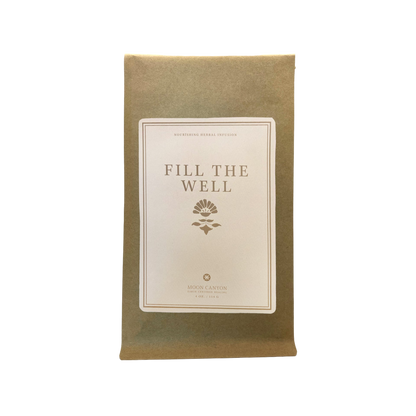 A brown paper package labeled "Fill The Well Herbal Infusion" with a simple floral emblem beneath the text. The label also reads "Nourishing Herbal Infusion," emphasizing self care, and includes the branding "Moon Canyon Healing.