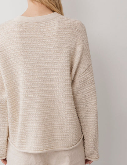 A person with long blonde hair is seen from the back, wearing Wol Hide's Thermal Sweater : Natural and light pants, set against a plain white background.