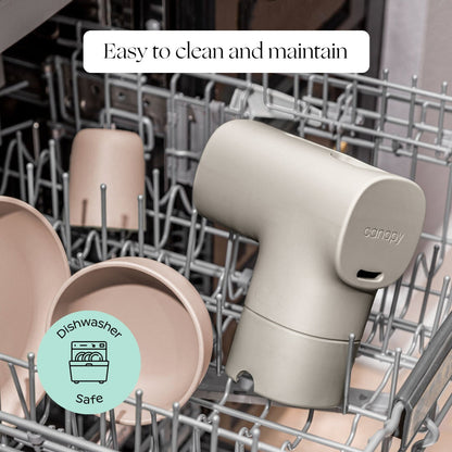 A beige Canopy Bath Tub Filter and its parts sit on the top rack of a dishwasher. Overlay text says, "Easy to clean and maintain," with a "Dishwasher Safe" icon in the bottom left corner. Fulfilled by Canopy.