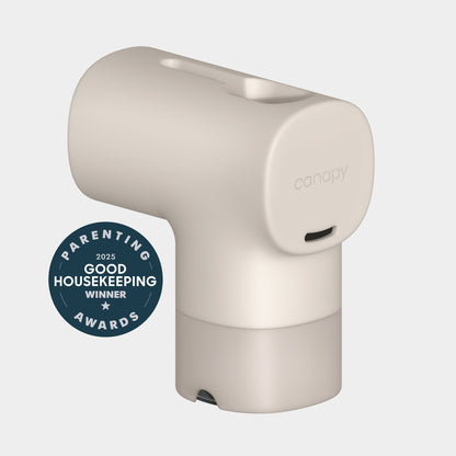 A beige Canopy Bath Tub Filter with a modern, minimalist design sits beside a round "2025 Good Housekeeping Winner Parenting Awards" badge. The filter features a small port, subtle "canopy" logo, and is Fulfilled by Canopy.