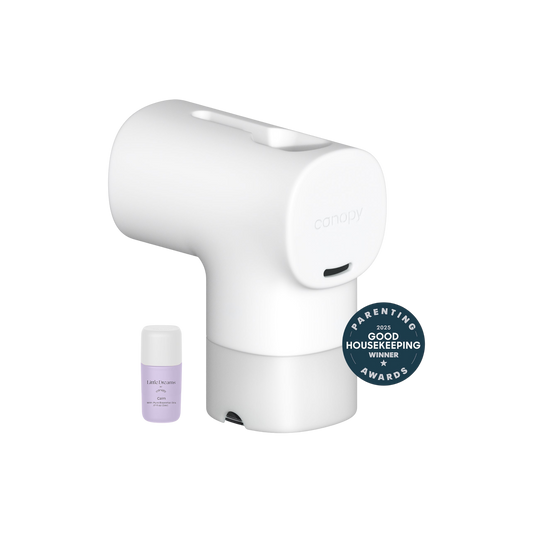 White A Canopy Baby Bath Tub Filter with a small essential oil bottle beside it—ideal for sensitive skin. The product features a "Parenting Good Housekeeping Awards Winner 2023" badge.