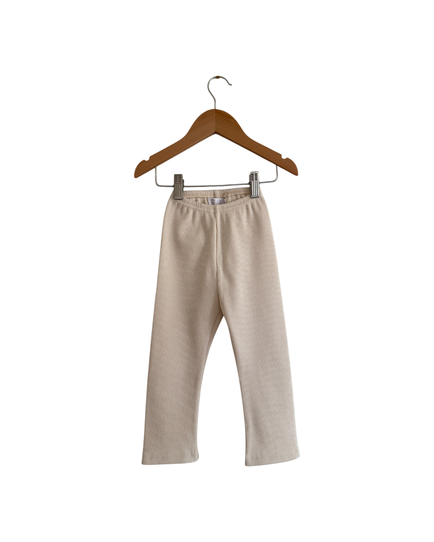 The FAVORIS rib pant by cabane childrenswear is a beige, straight-leg kids’ pant with an elastic waistband, handmade in Vancouver from natural cotton rib, shown on a wooden hanger against a plain white background.