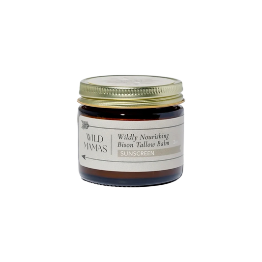 A small brown glass jar with a gold lid labeled "Wild Mamas Wildly Nourishing Bison Tallow Balm - Sunscreen" sits against a white background, highlighting regenerative skincare with Non-Nano Zinc Oxide.