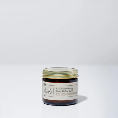 A small brown glass jar with a gold lid, labeled "Wildly Nourishing Bison Tallow Balm - Sunscreen" by Wild Mamas, sits on a plain white background—a natural choice for regenerative skincare.