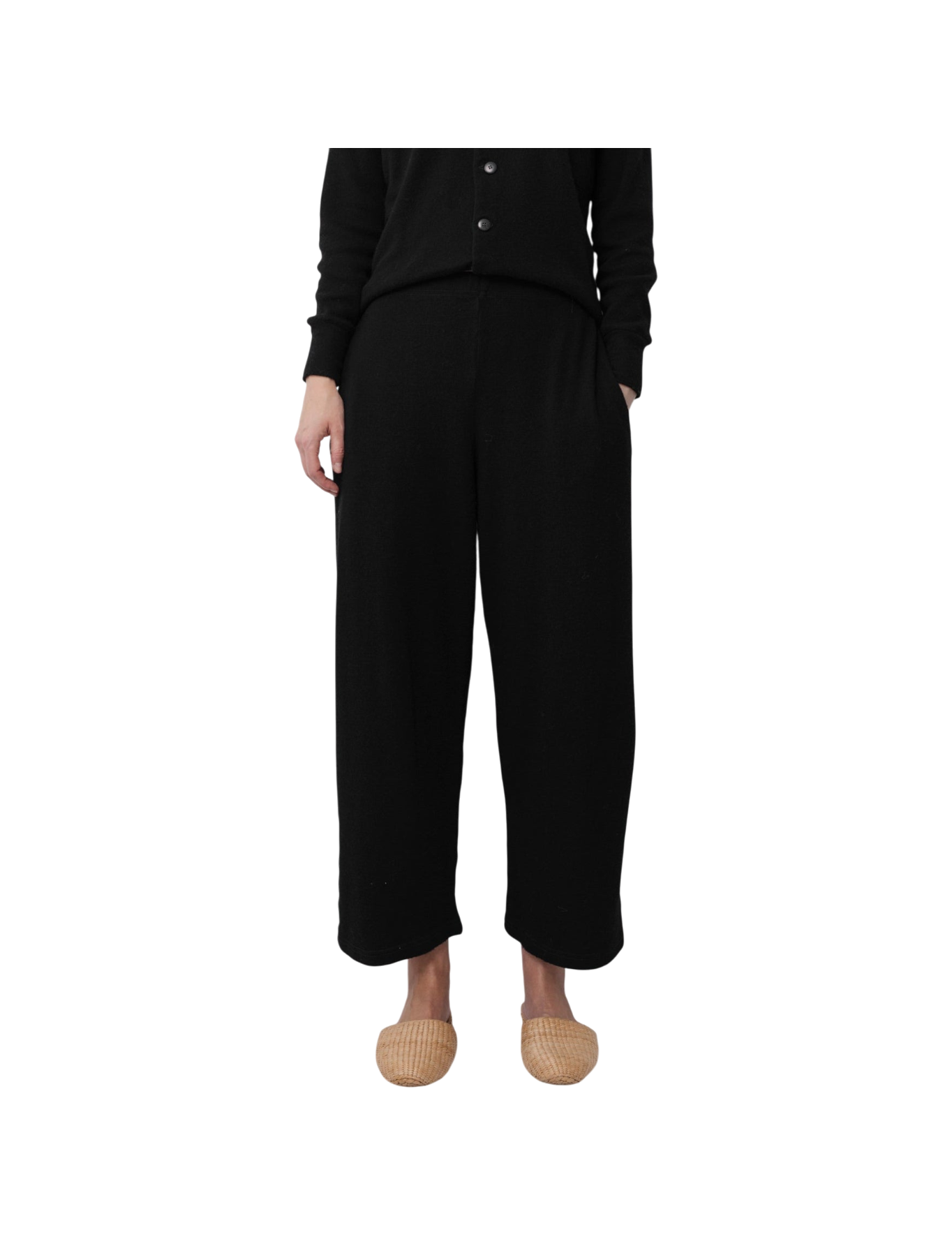 A person models the Wol Hide Wool Wide Leg pants in Onyx with a matching black buttoned top and light woven slippers, standing against a plain white background. Only their lower body is visible.