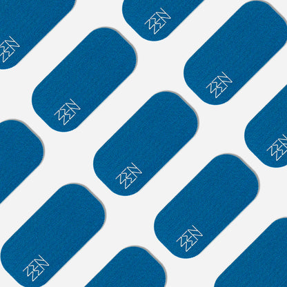 Blue rectangular patches with rounded corners are arranged diagonally on a white background. Each Zenzentape Pacific Breeze Mouthtape patch displays a simple white zigzag in one corner, crafted from organic bamboo silk for gentle sleep support.