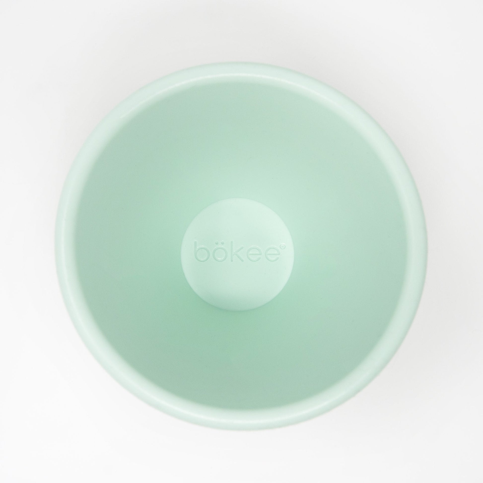A top-down view of an empty, light green bökee Baby Bottle Holder, crafted from BPA-free silicone, shown on a white background.
