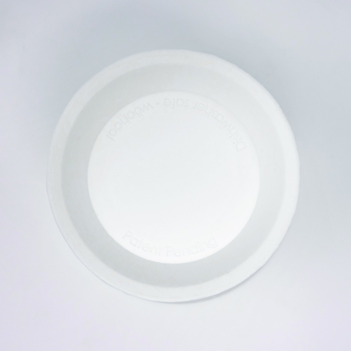 A white, round paper bowl viewed from above on a plain white background features an inner rim subtly embossed with text reminiscent of the elegant simplicity characteristic of the bökee Baby Bottle Holder, One-Handed Bottle Prep by bökee.