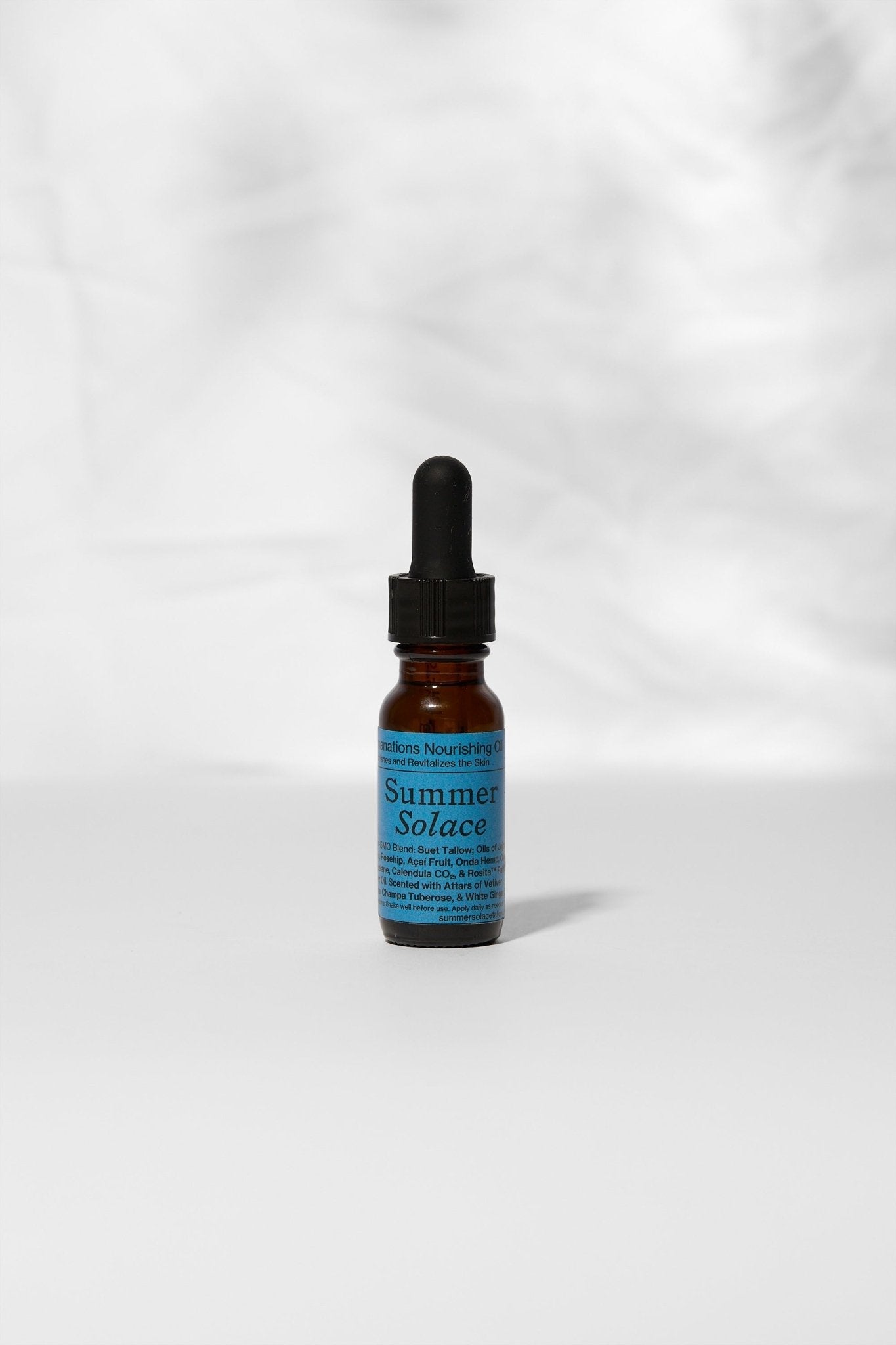 A small amber glass dropper bottle labeled "Summer Solace Tallow" with a blue label stands on a white surface, featuring Emanations Profound Face Oil—Deeply Nourishing, with champa, tuberose & white ginger lily, against a simple white background.