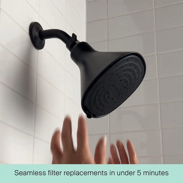 A person quickly swaps a black Canopy Filtered Showerhead filter on a tiled wall, showing how easy it is to replace. Fulfilled by Canopy. Caption: “Seamless filter replacements in under 5 minutes.”.