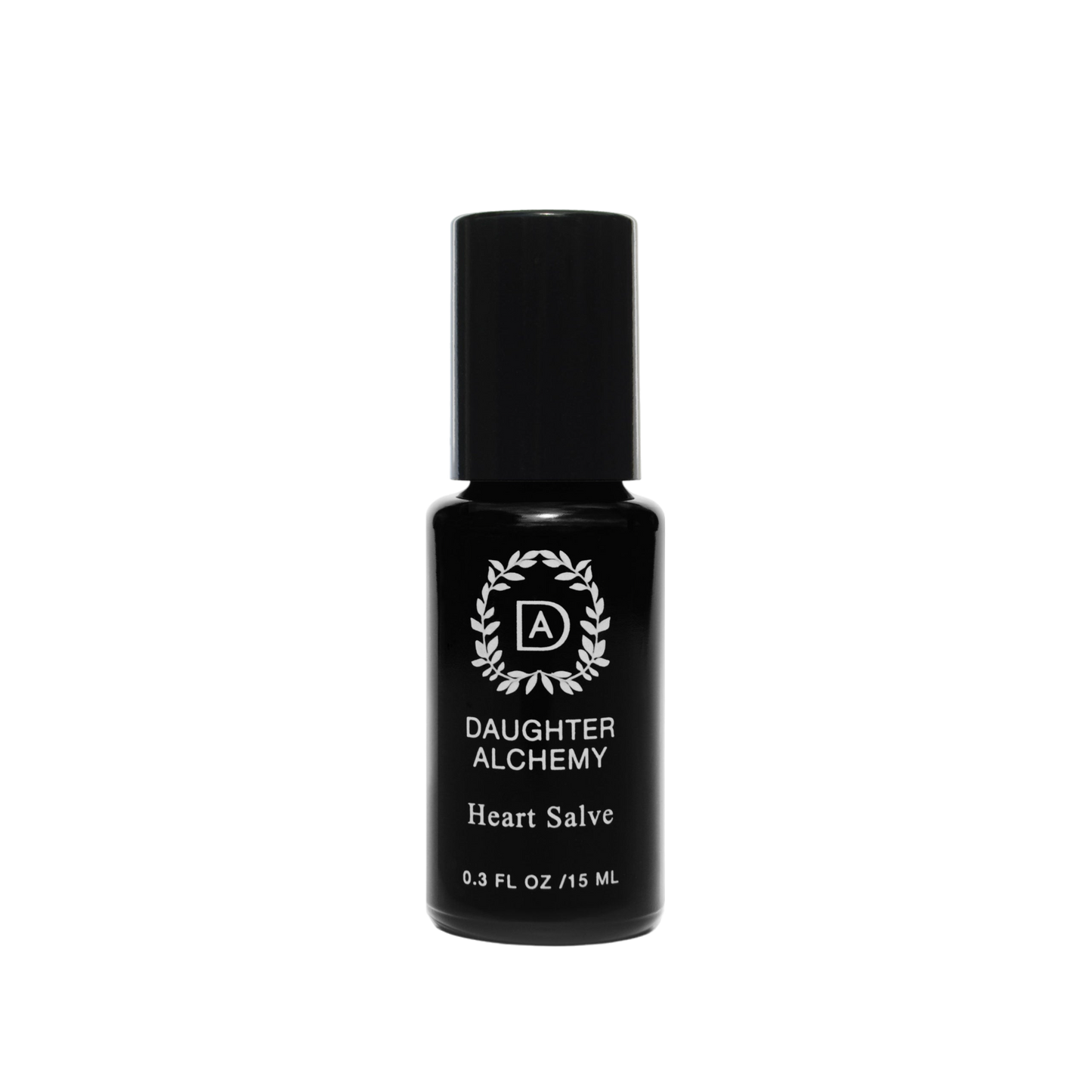 A small black bottle of Heart Salve® Botanical Nurturing Oil by Daughter Alchemy, crafted with organic ingredients, is displayed against a black background. The label features a white logo with a wreath design around the initials "DA" above the product name and indicates the bottle contains 0.3 fl oz (15 ml) of nurturing oil salve.