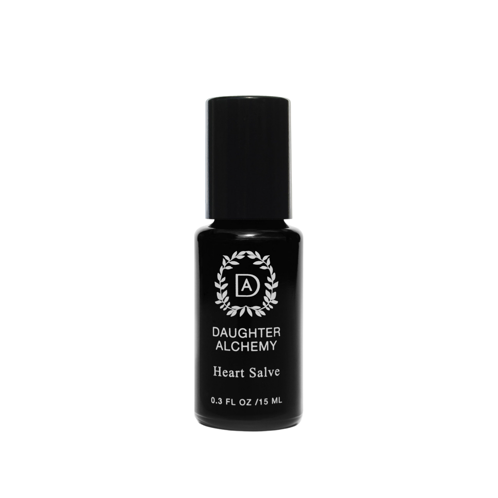 A small black bottle of Heart Salve® Botanical Nurturing Oil by Daughter Alchemy, crafted with organic ingredients, is displayed against a black background. The label features a white logo with a wreath design around the initials "DA" above the product name and indicates the bottle contains 0.3 fl oz (15 ml) of nurturing oil salve.