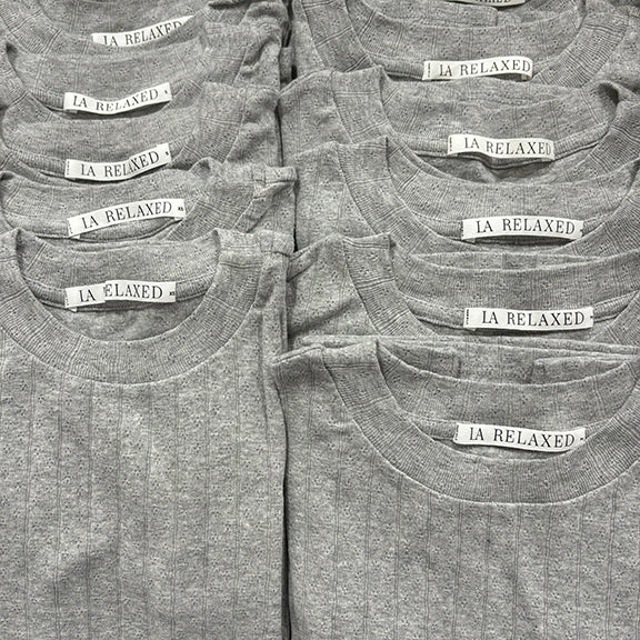 A neatly arranged group of Organic Texture Tees in gray, made from organic cotton with a subtle vertical stripe texture, each showing visible "LA RELAXED" tags.