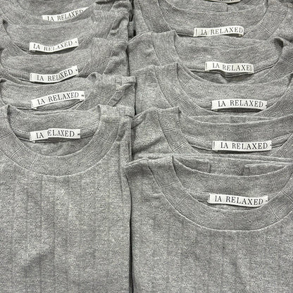A neatly arranged group of Organic Texture Tees in gray, made from organic cotton with a subtle vertical stripe texture, each showing visible "LA RELAXED" tags.