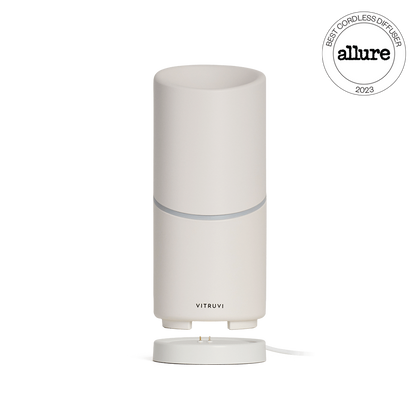 The elegant Move Diffuser by Vitruvi features a smooth, cylindrical design in a light, neutral color. This cordless diffuser doesn't require a plug and has been named the "Best Cordless Diffuser" by Allure in 2023. Its detachable base allows for optimal efficiency in scenting every corner of your space.