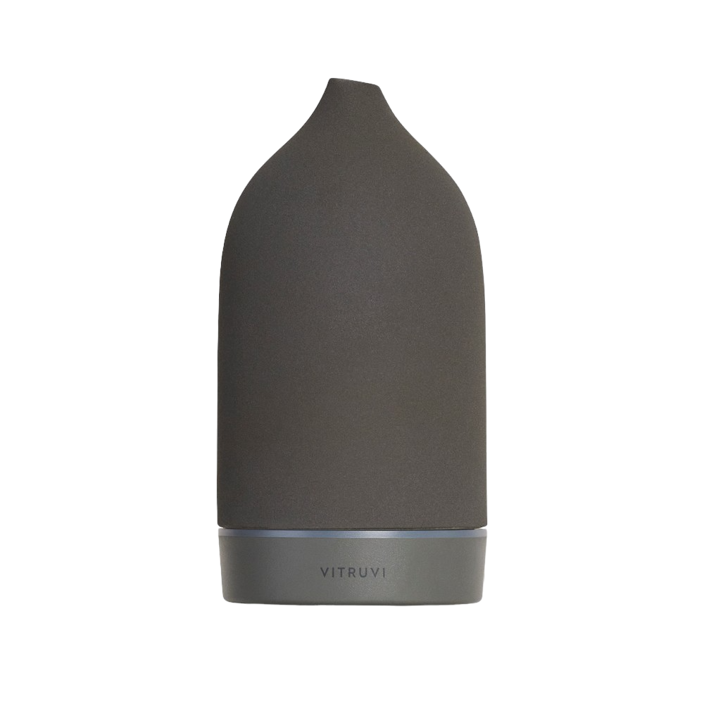 The Vitruvi Stone Diffuser features a sleek, black matte finish with a modern, minimalist design. Its slightly tapered top and smooth surface add to its elegant aesthetic. The brand name "VITRUVI" is subtly embossed near the base, making it an exquisite addition to your home decor for using pure essential oils.