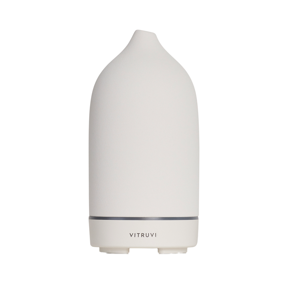 The Stone Diffuser by Vitruvi is a modern, white, cone-shaped essential oil diffuser with the brand name "Vitruvi" elegantly displayed on its lower section. Its minimalist design features a narrow top and slightly wider base, making it an ideal addition to home decor while effectively diffusing pure essential oils.