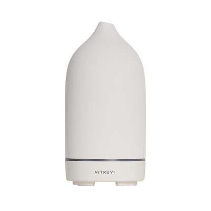 The Stone Diffuser by Vitruvi is a modern, white, cone-shaped essential oil diffuser with the brand name "Vitruvi" elegantly displayed on its lower section. Its minimalist design features a narrow top and slightly wider base, making it an ideal addition to home decor while effectively diffusing pure essential oils.