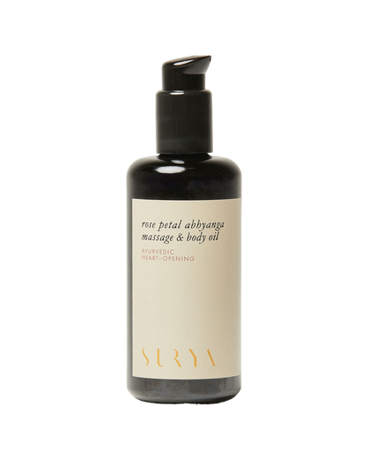 A bottle of Rose Petal Body Oil from the brand Surya, featuring a pump dispenser. The cream-colored label with gold lettering reads "Ayurvedic Heart-Opening." Handmade by Martha, the sleek black bottle captures the essence of rose essential oil.