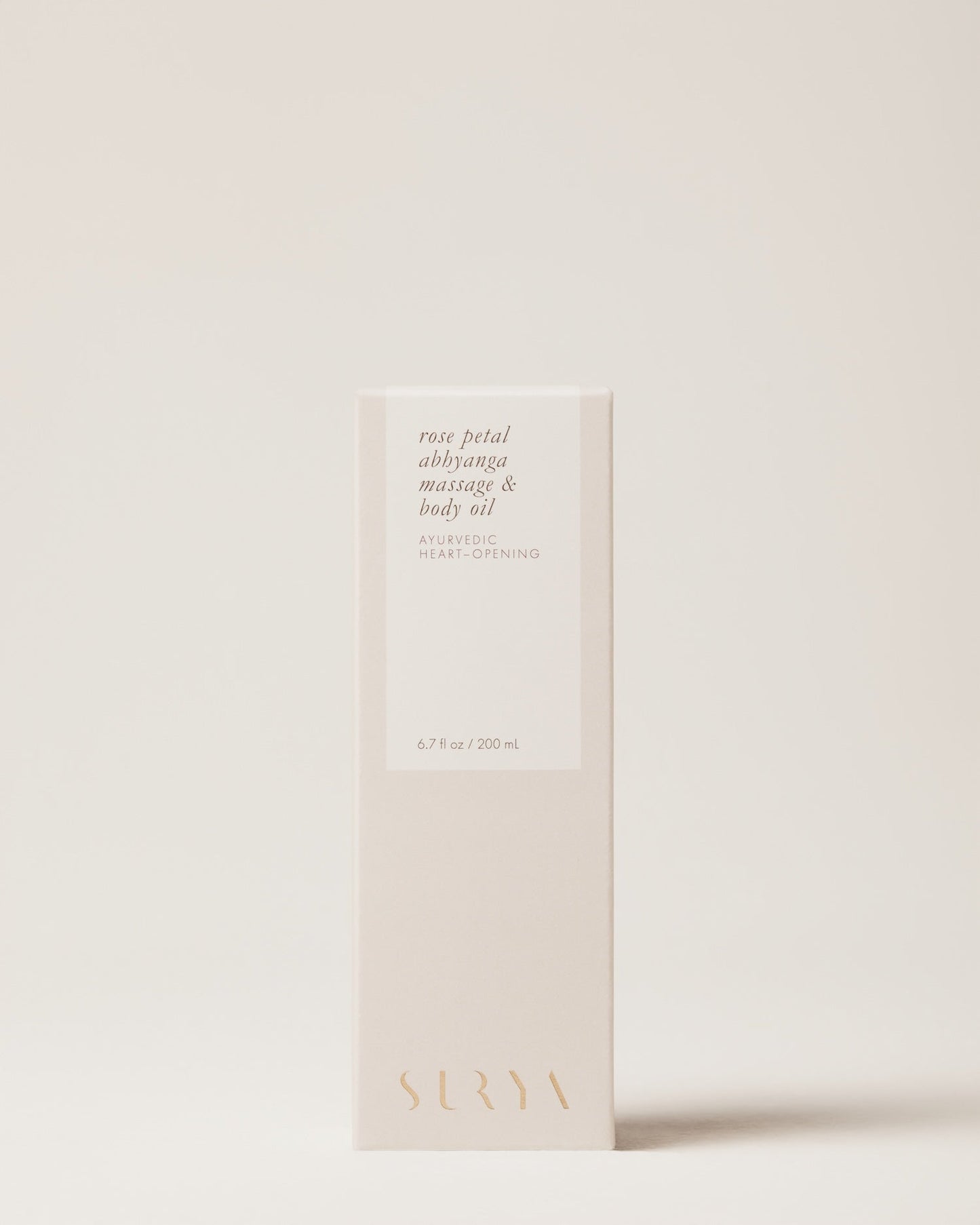 A beige box of Surya Rose Petal Body Oil, labeled "heart-opening," features minimalist gold and white text. This 6.7 fl oz (200 mL) product is handmade by Martha using organic ingredients for a pure, luxurious experience.