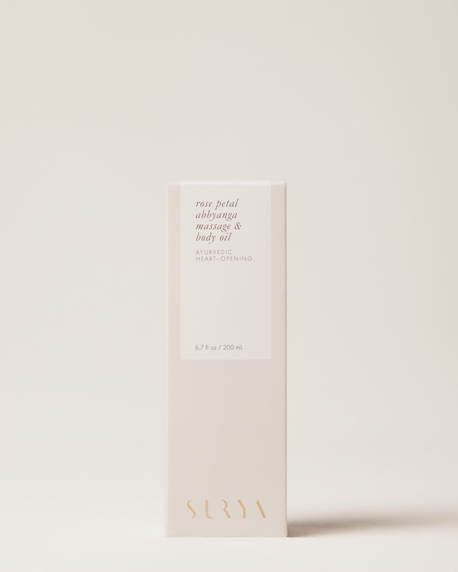A beige box of Surya Rose Petal Body Oil, labeled "heart-opening," features minimalist gold and white text. This 6.7 fl oz (200 mL) product is handmade by Martha using organic ingredients for a pure, luxurious experience.