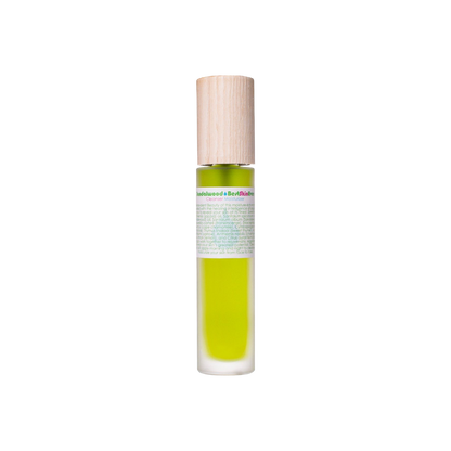 A glass bottle containing green liquid, capped with wood, and adorned with a label featuring colorful text. This elegant bottle houses the Best Skin Ever Cleanser- Sandalwood from Living Libations, likely a scented or cosmetic product infused with essential oils.