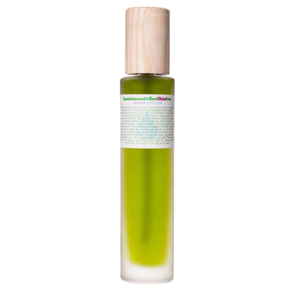 A green cylindrical bottle with a wooden cap, labeled "Best Skin Ever Cleanser - Sandalwood" by Living Libations. The bottle contains further text in small print and is filled with a green liquid, likely the cleanser enhanced with organic essential oils.
