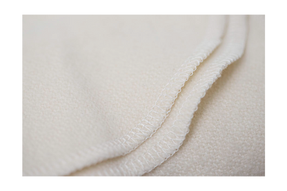 Close-up of a Shepherd's Dream Organic Merino Wool Blanket in beige, highlighting its textured surface and precise, parallel stitching along the edge.