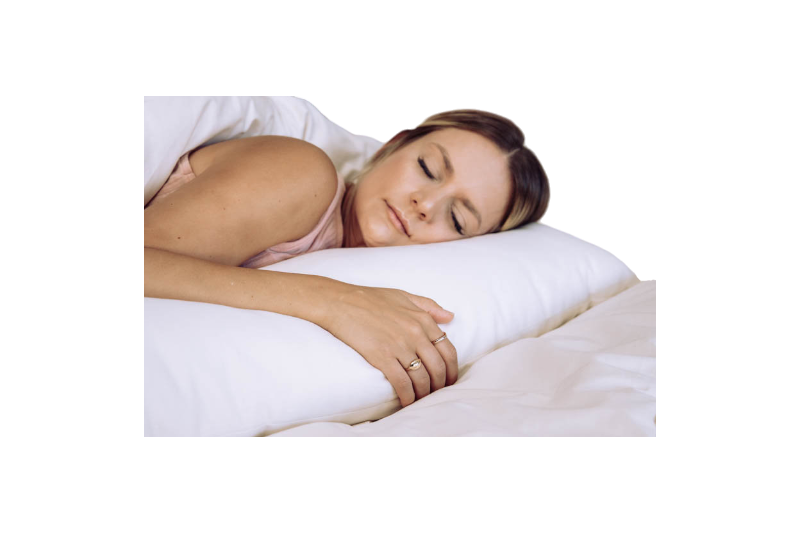 A person peacefully sleeping on the Shepherd's Dream Wool Filled Body Pillow with an organic cotton cover, nestled under a white blanket. Their face is relaxed and they are lying on their side, with a hand resting softly on the wool-filled pillow.