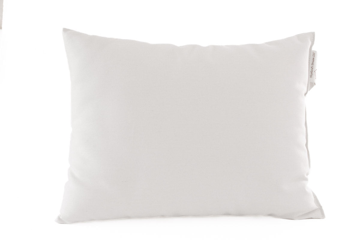 The Child's Sleep Pillow by Shepherd's Dream, featuring a natural wool filling for a soft, smooth texture, is positioned centrally against a white background. A small fabric tag can be seen on the side.