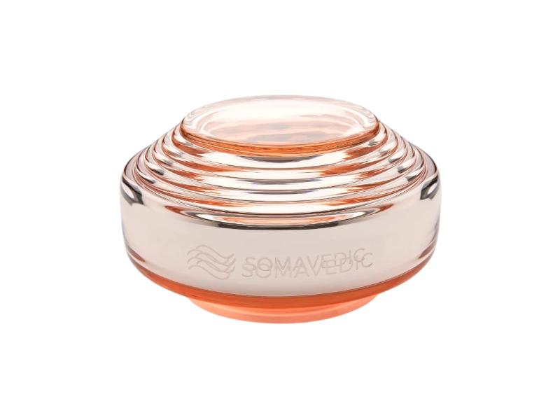 Rosalin by Somavedic USA is a transparent, round, layered glass device with a peach tint, supporting feminine well-being. It features the engraved word "SOMAVEDIC" and a wavy logo on the side.