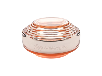 Rosalin by Somavedic USA is a transparent, round, layered glass device with a peach tint, supporting feminine well-being. It features the engraved word "SOMAVEDIC" and a wavy logo on the side.