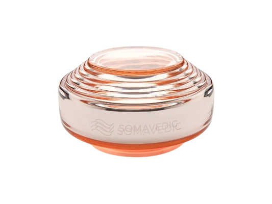 Rosalin by Somavedic USA is a transparent, round, layered glass device with a peach tint, supporting feminine well-being. It features the engraved word "SOMAVEDIC" and a wavy logo on the side.