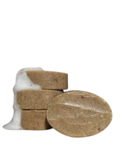 Four oval Wild Mamas Wild Bison Tallow Gentle Exfoliating Soap Scrub bars (Madagascar Vanilla Bean + Manuka Honey) are stacked, the top covered in white foam. One bar in front shows its smooth, textured surface against a plain white background.