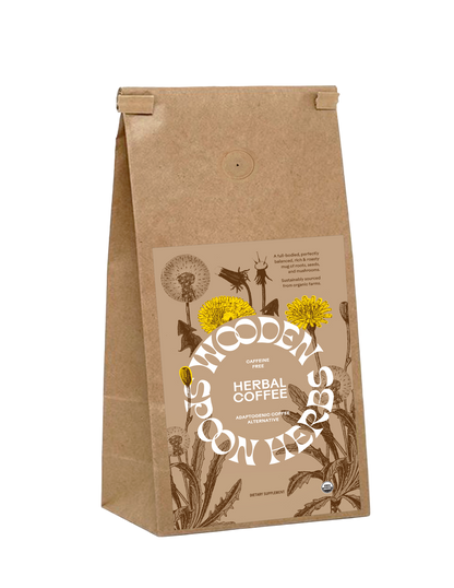 A brown paper bag labeled "WOODED SPOON HERBS" containing "Herbal Coffee," a caffeine-free blend featuring adaptogenic herbs, ashwagandha, and adaptogenic mushrooms. The front displays illustrations of yellow dandelions and other herbs. The bag has a folded top closure.